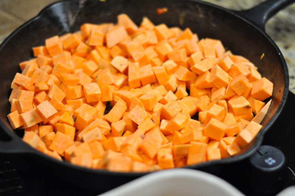 up close image of black skillet with diced sweet potatoes in it